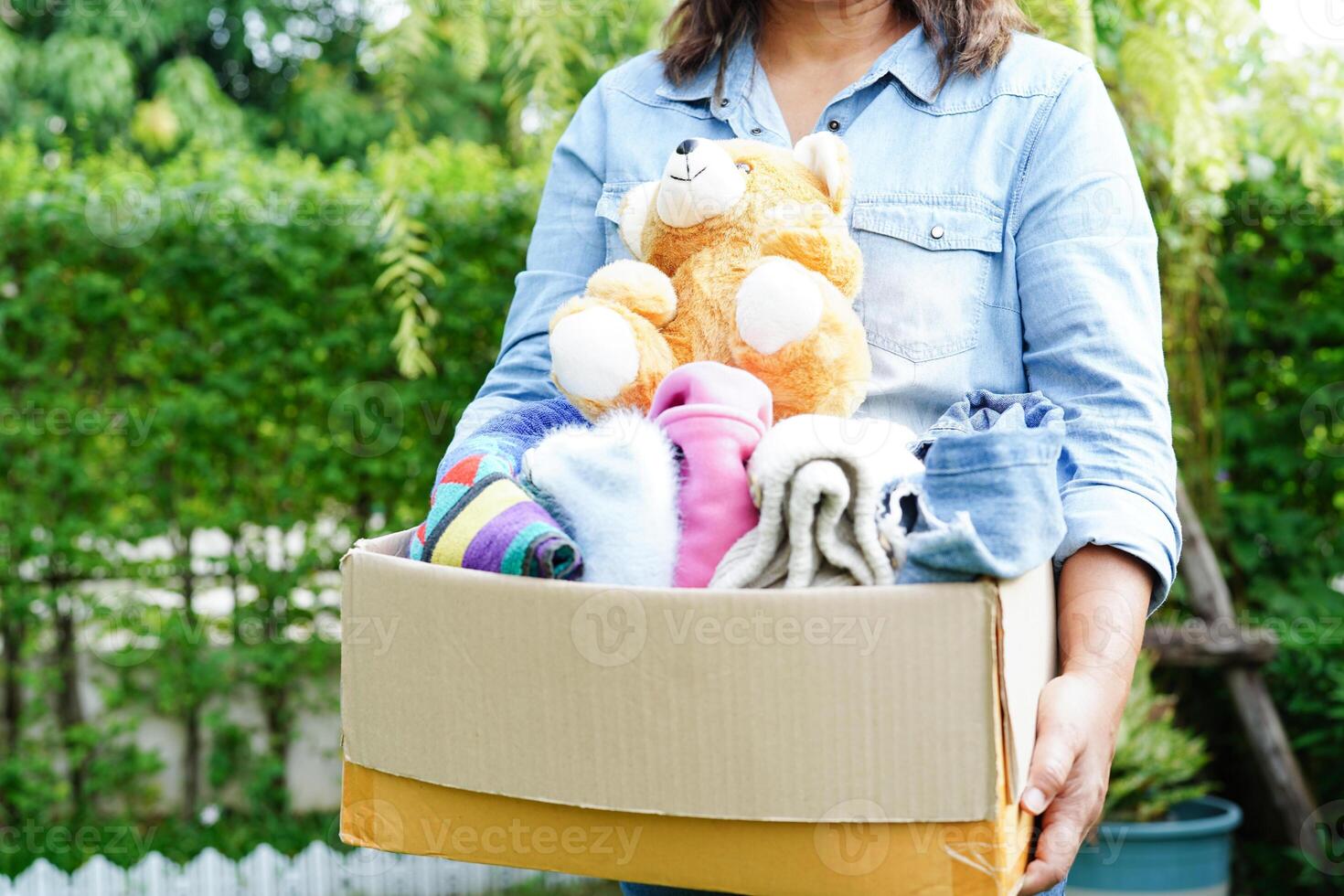 Volunteer collect cloth and doll in cardboard box to donate. photo