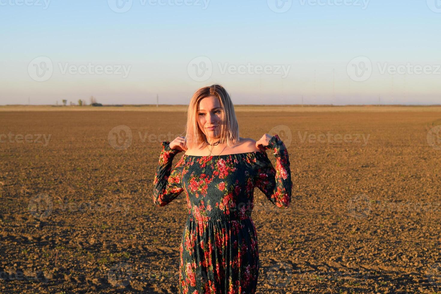 mujer en un arado campo en un negro rojo vestir en un puesta de sol antecedentes. foto