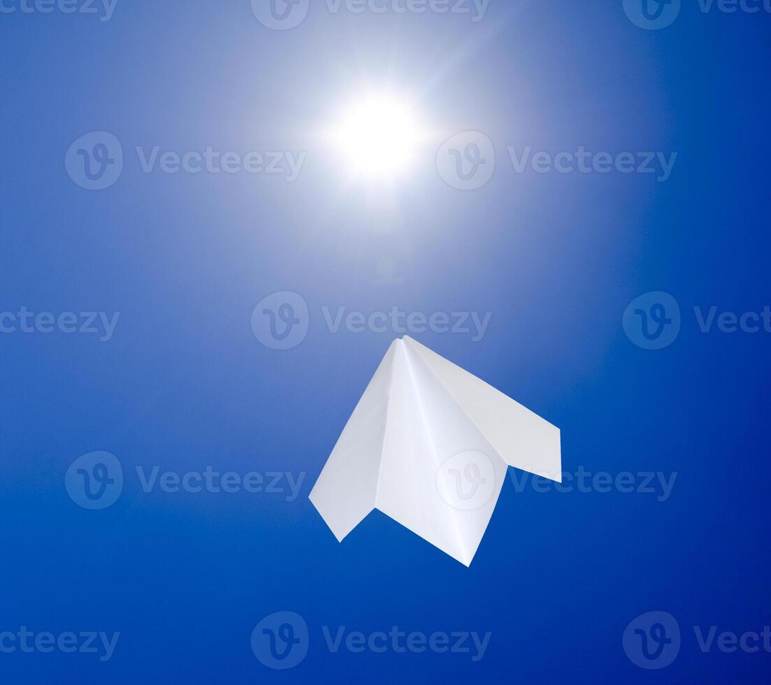 White paper airplane against the blue sky flying towards the sun. The symbol of freedom and privacy on the Internet photo