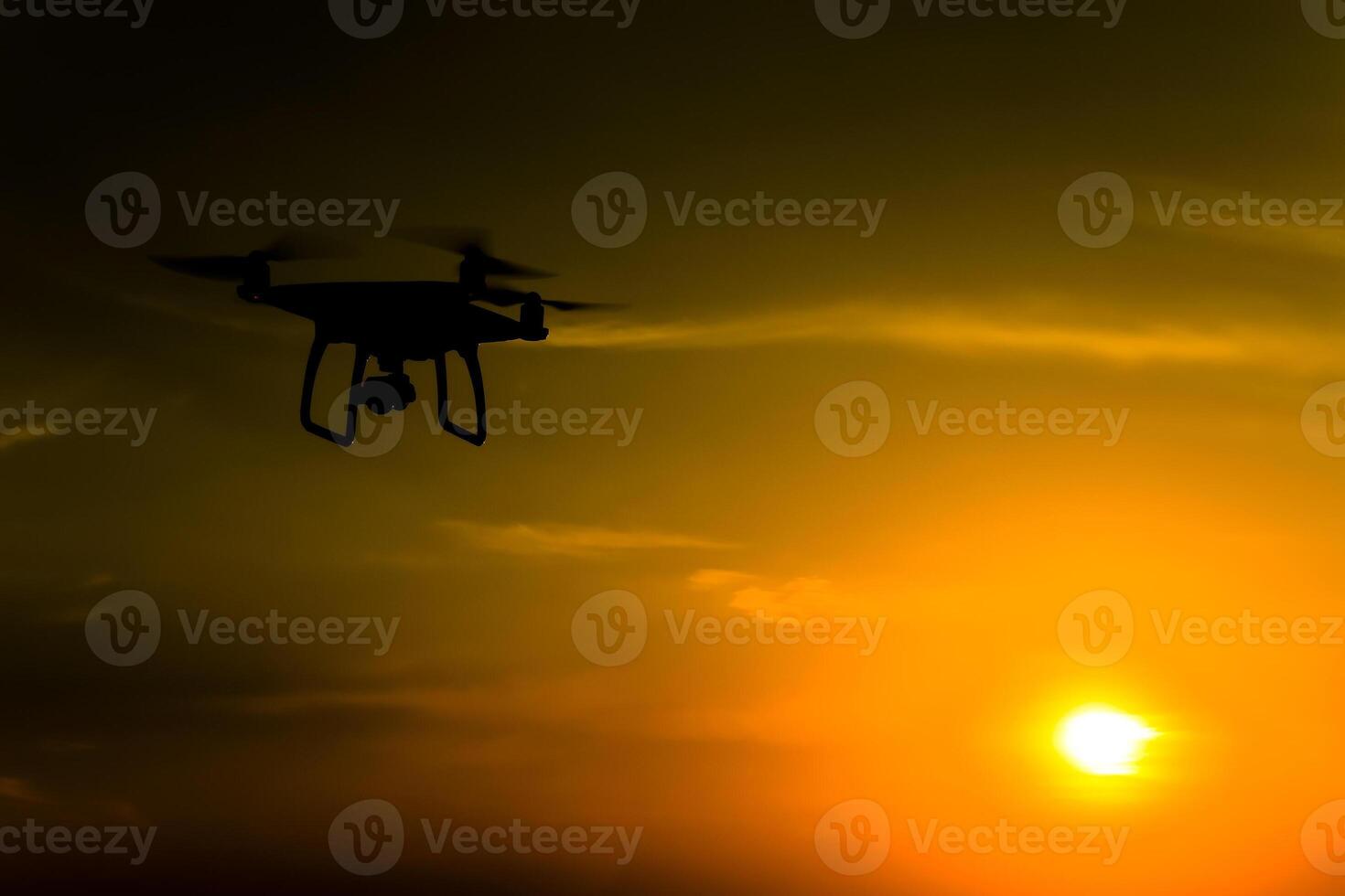 Quadrocopters silhouette against the background of the sunset. Flying drones in the evening sky photo