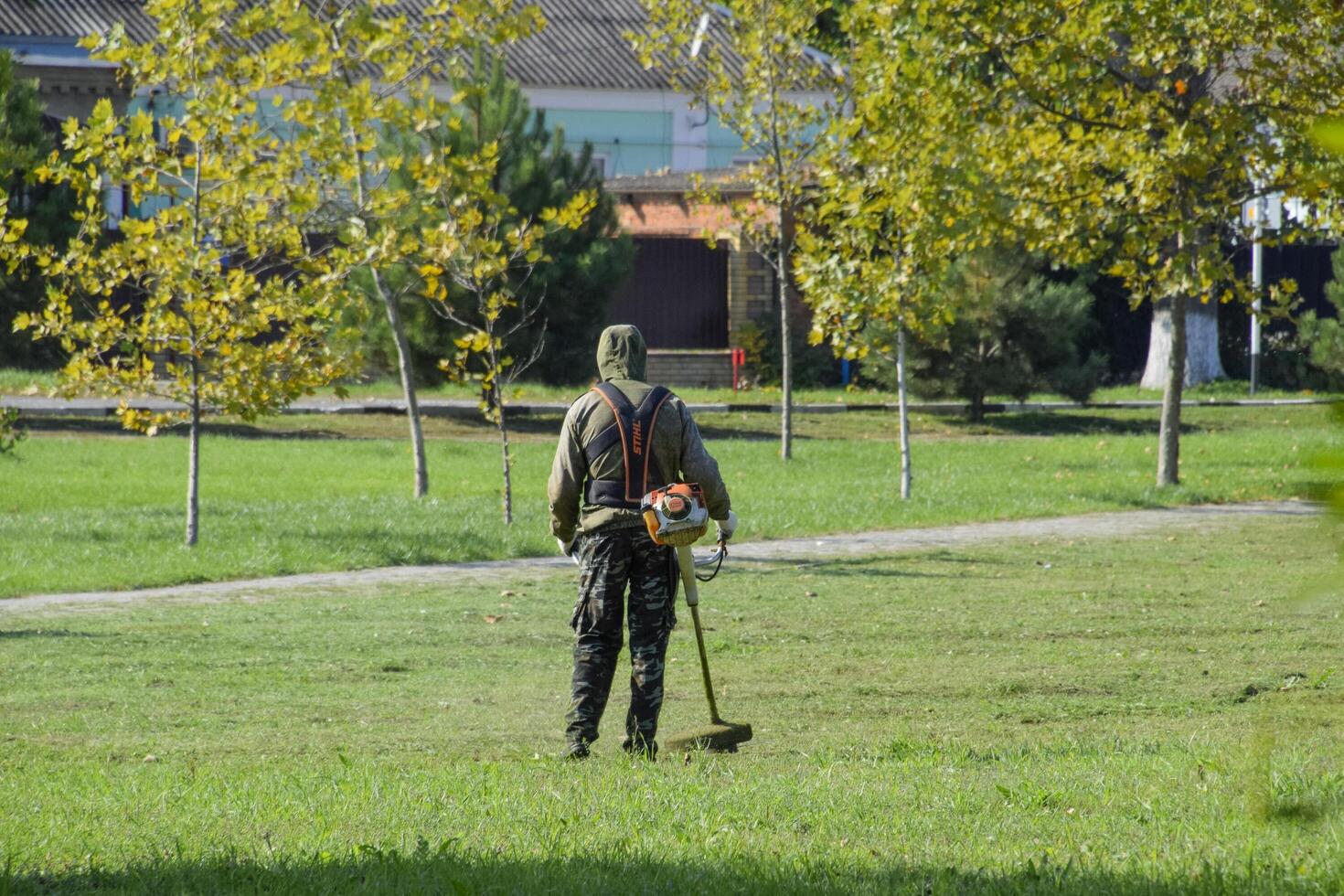 worker mowing grass with a gasoline brush. Trimmer. photo