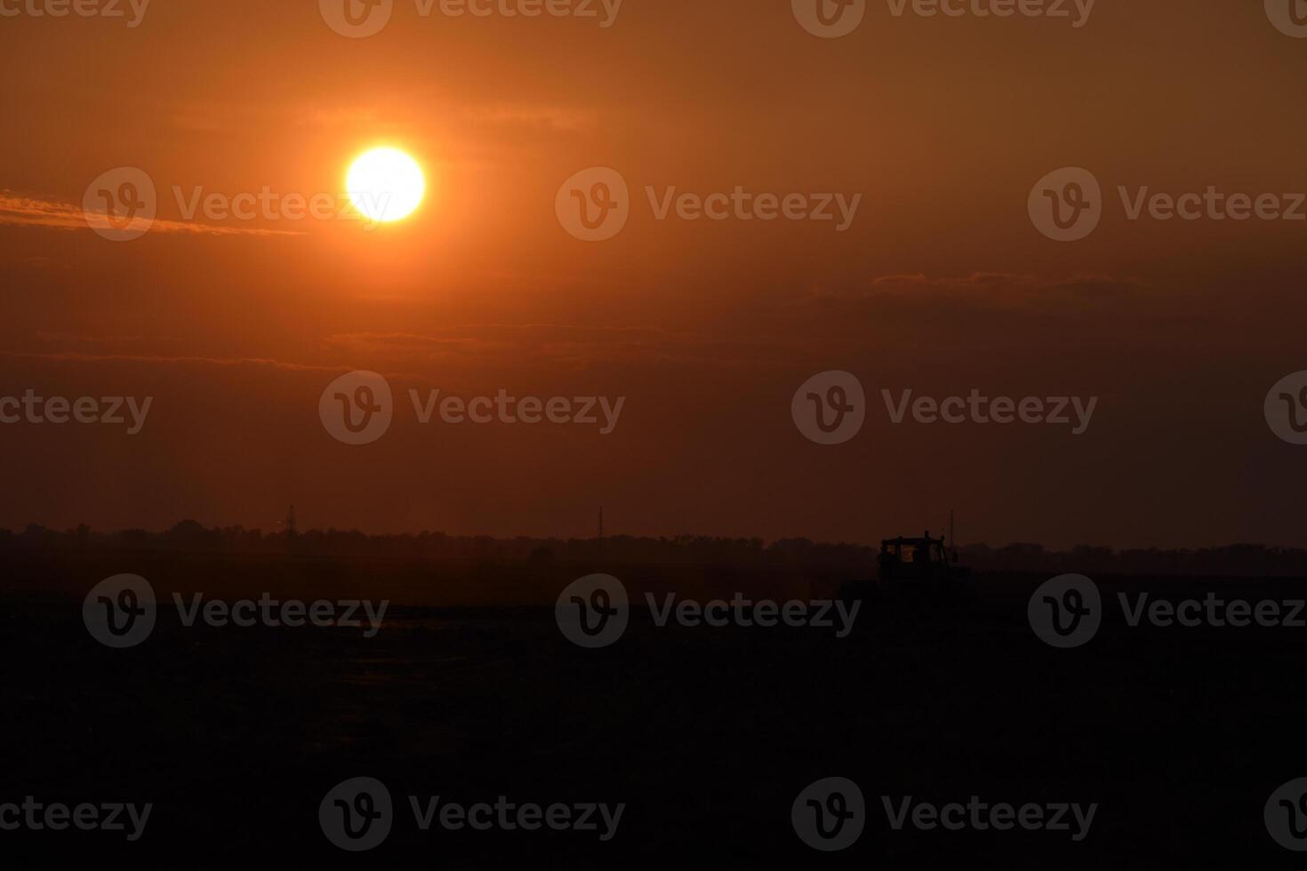 Tractor plowing plow the field on a background sunset. tractor silhouette on sunset background photo