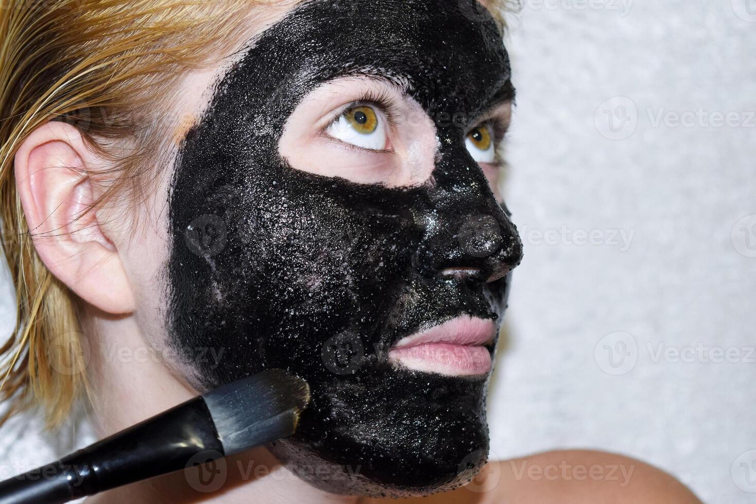 Girl in a cosmetic black mask. Cleansing mask of aspirin and activated carbon. Black cosmetic face mask. photo