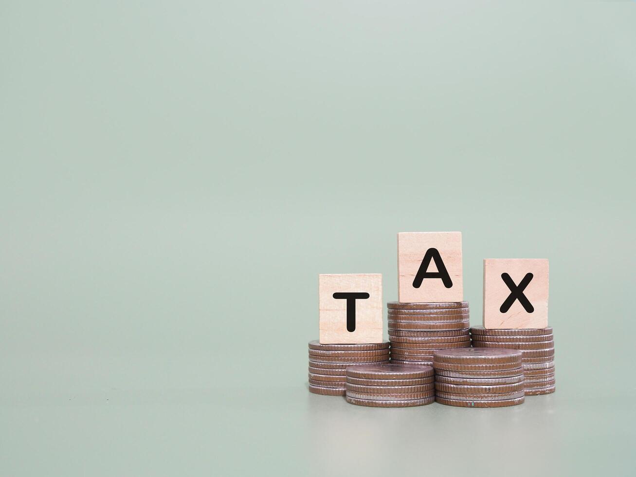 Wooden blocks with the word TAX on stack of coins. The concept about saving money and manage time to paying tax photo