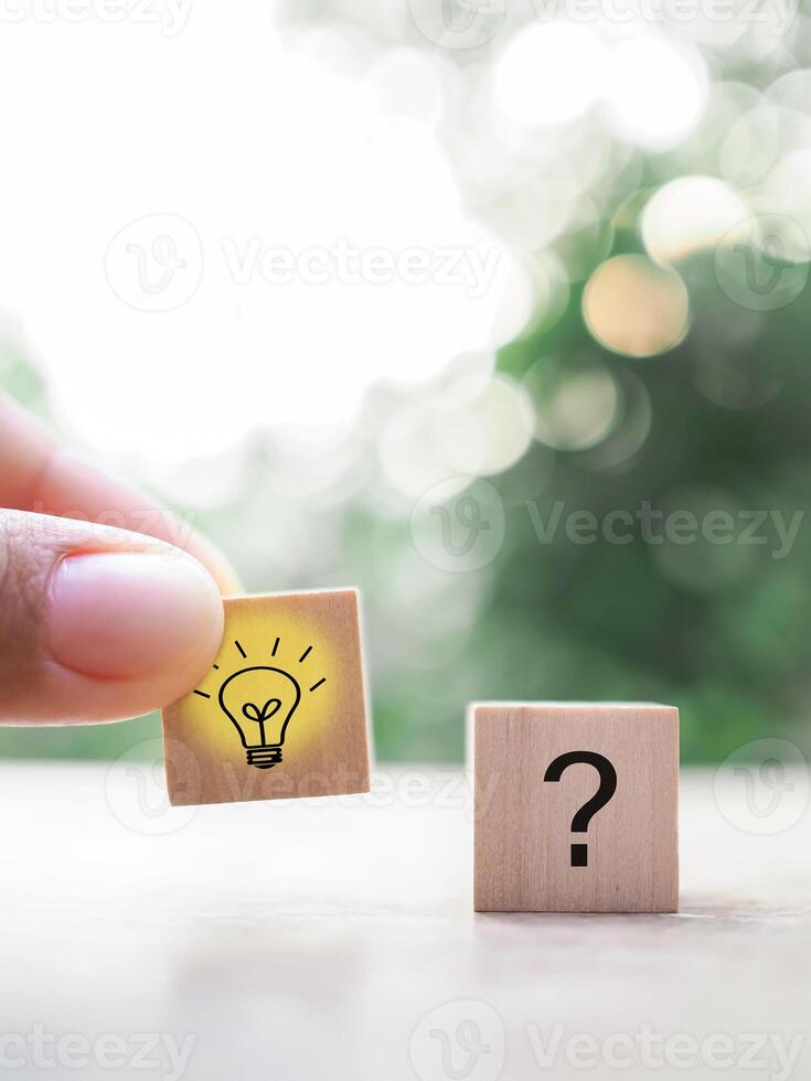 Close up hand arranging wooden block with light bulb and wooden block with question mark for leadership, creative, idea, innovation concept. photo