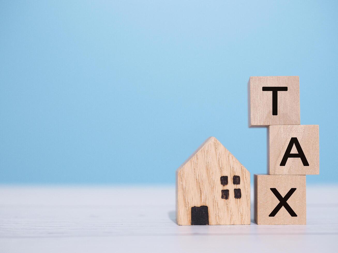 Miniature house and Wooden blocks with the word TAX. The concept of payment tax for house, Property investment, House mortgage, Real estate photo