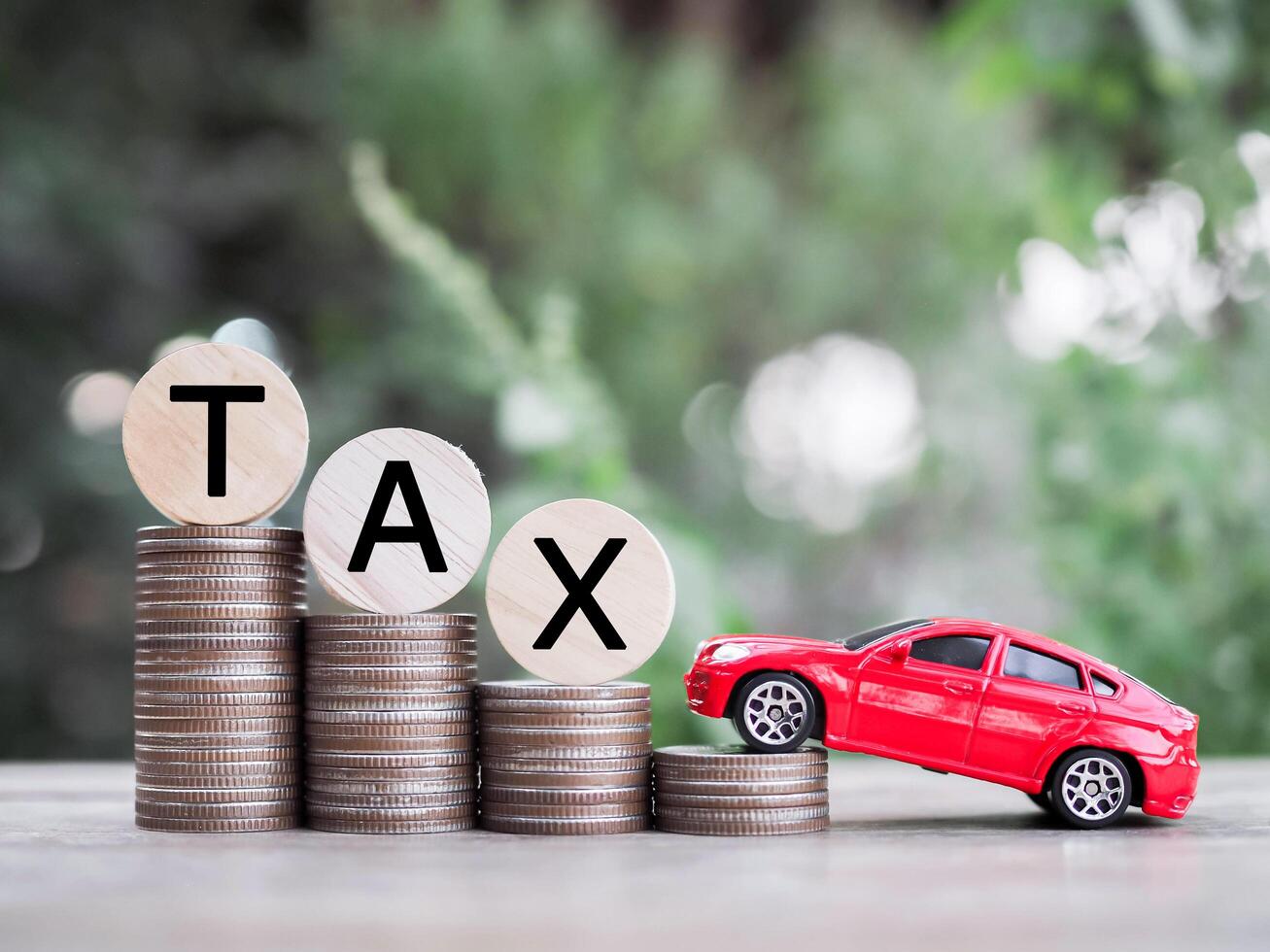 Toy car and wooden blocks with the word TAX on stack of coins. The concept of saving and manage money to success transportation, Paying tax and car loan photo