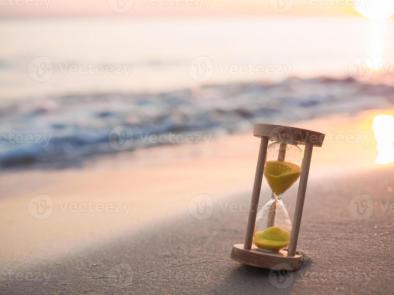 Hourglass on the beach in the sunset time. The concept about countdown to Summer, Travel, Vacation and Relaxation. photo