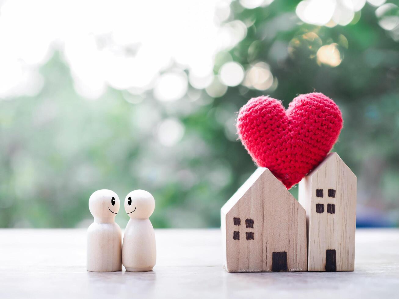 Wooden figure couple happy face and Miniature house with heart. The concept of romantic feelings, family relationship. photo