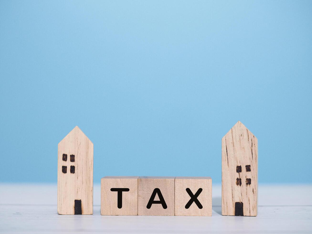 Miniature house and Wooden blocks with the word TAX. The concept of payment tax for house, Property investment, House mortgage, Real estate photo
