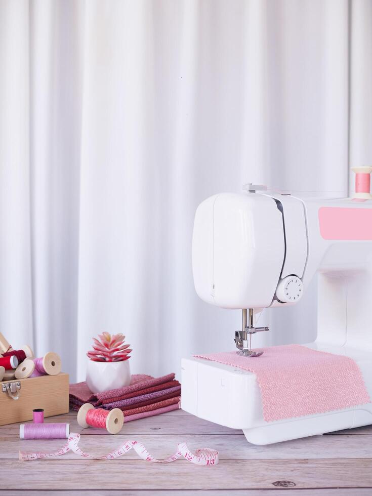 Close up sewing machine working with pink fabric, sewing accessories on the table, stitch new clothing. photo