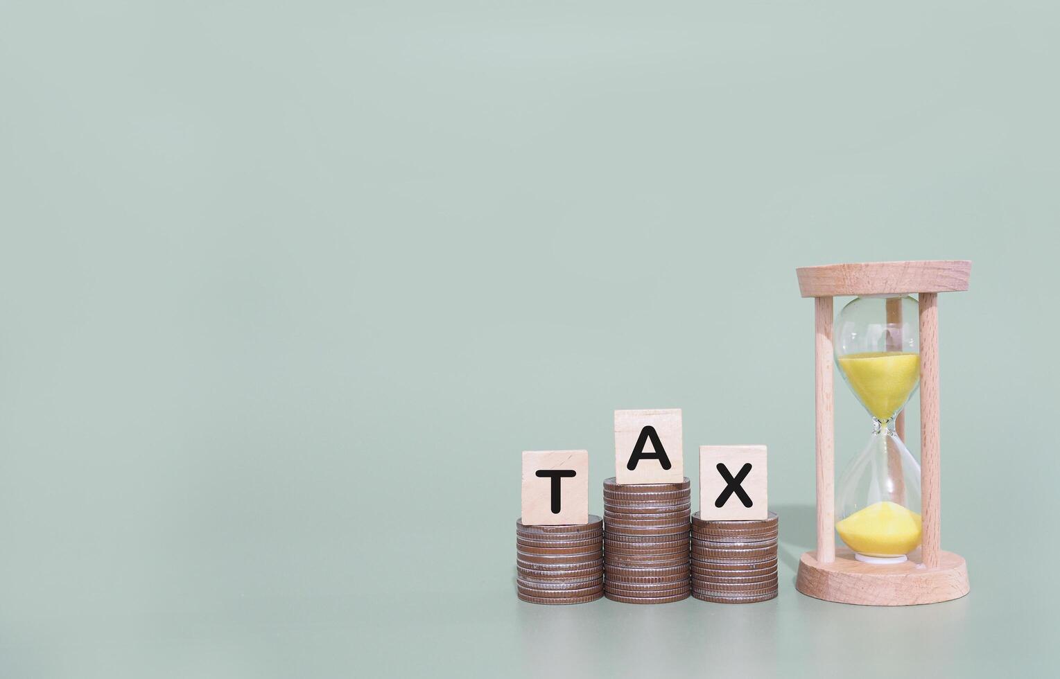 Hourglass, Wooden blocks with the word TAX on stack of coins. The concept about saving money and manage time to paying tax photo