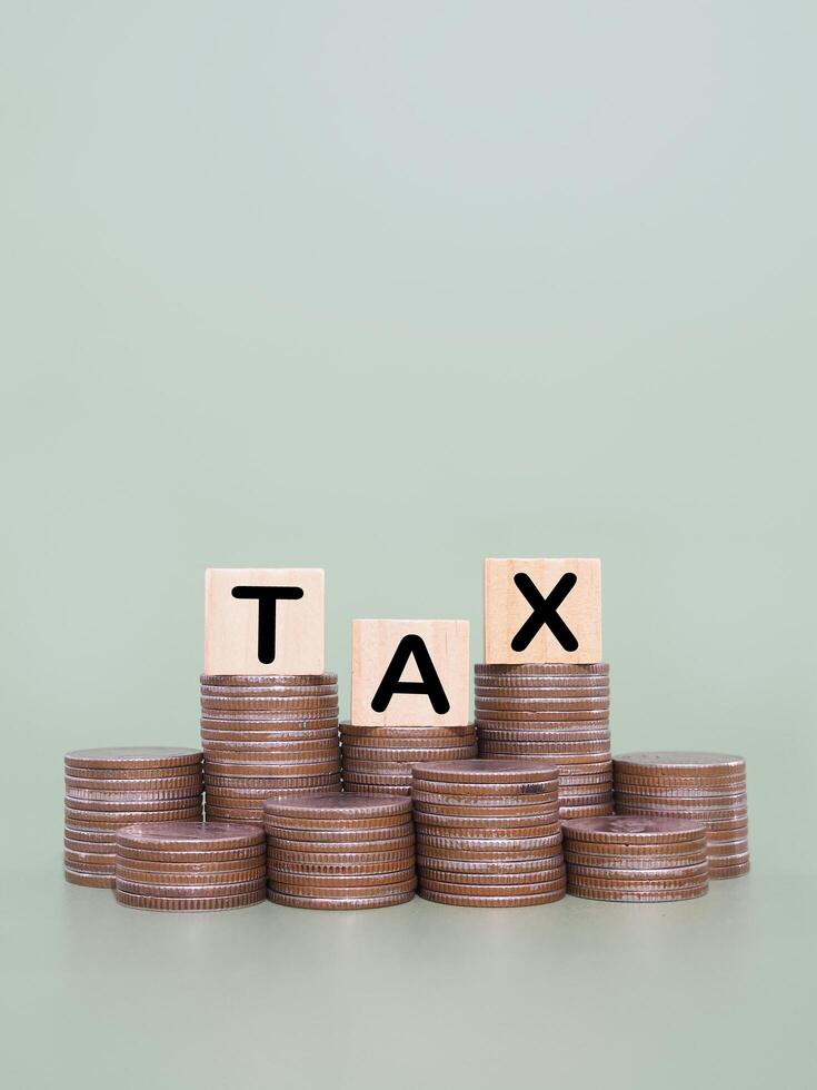 Wooden blocks with the word TAX and stack of coins. The concept about saving money and manage time to paying tax photo