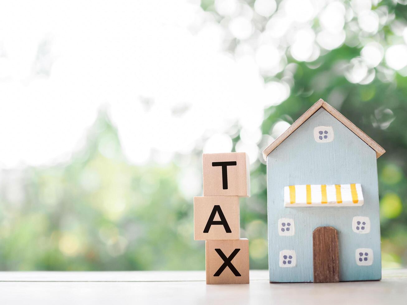 Miniature house and Wooden blocks with the word TAX. The concept of payment tax for house, Property investment, House mortgage, Real estate photo