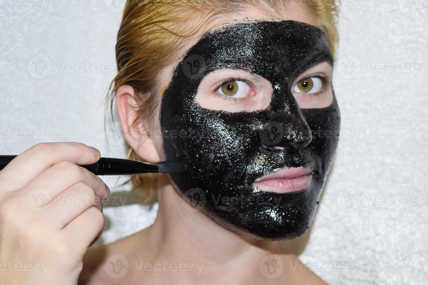 Girl in a cosmetic black mask. Cleansing mask of aspirin and activated carbon. Black cosmetic face mask. photo