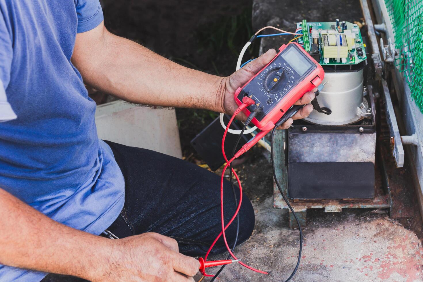 Electrician checking mainboard with multimeter outdoors at home. photo