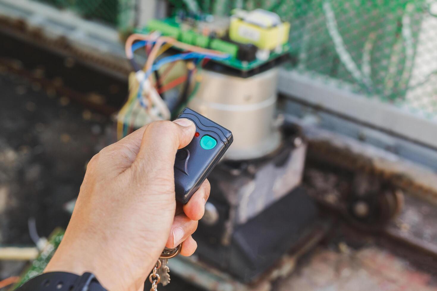 Man hand pressing remote control to open gate door. photo