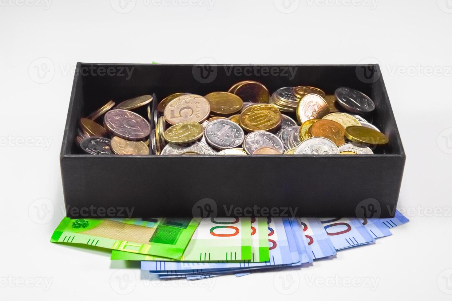 Coins of different denominations in a piggy bank box. Paper rubles under the piggy bank. New banknotes of Russia photo