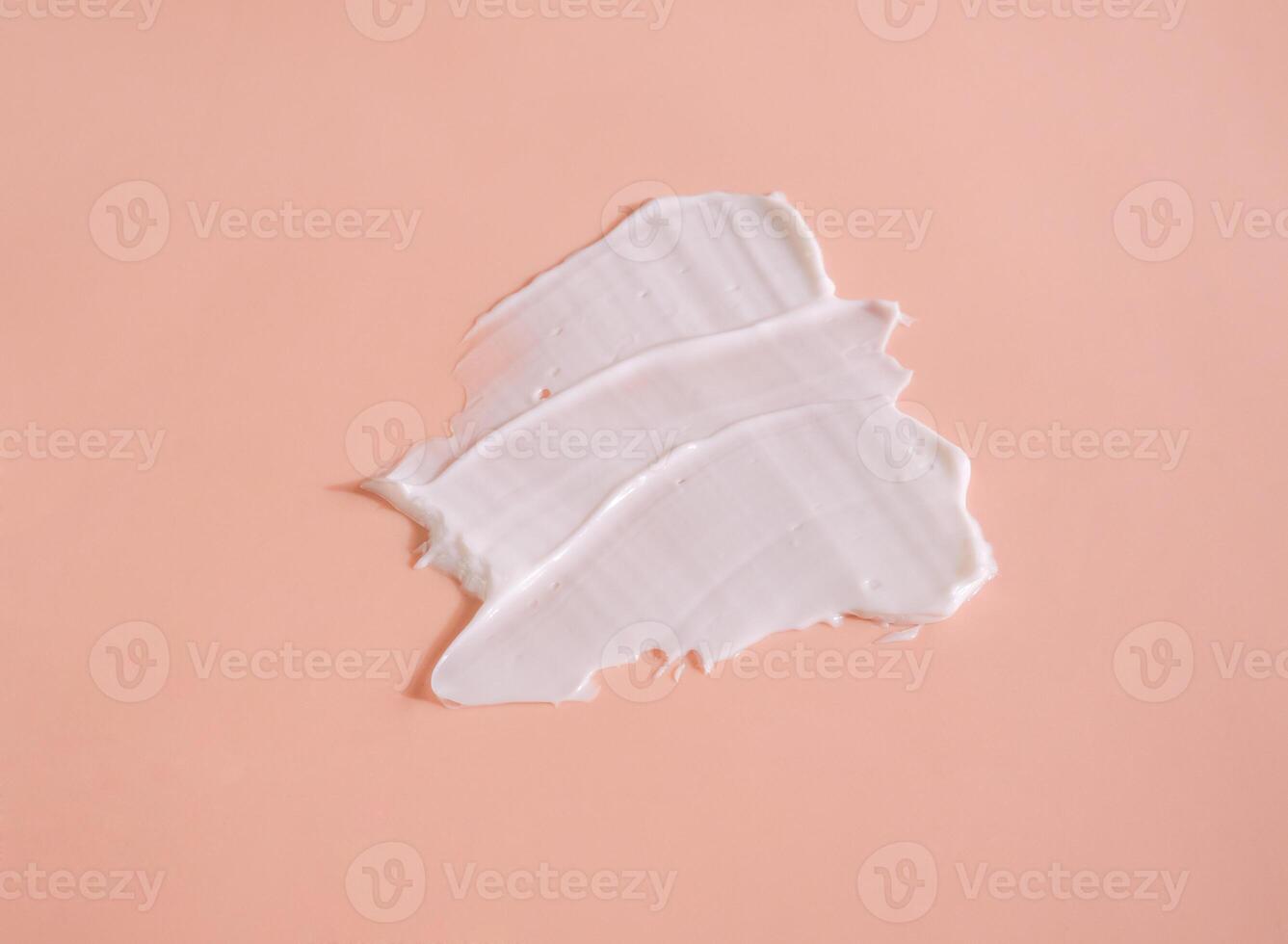 White smear of cosmetic cream on a beige background. Creamy foundation texture isolated. Smear of face cream. Close up of cream texture photo