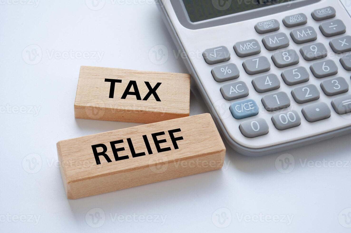 Tax relief text on wooden blocks on white cover background with calculator background. Taxation concept photo