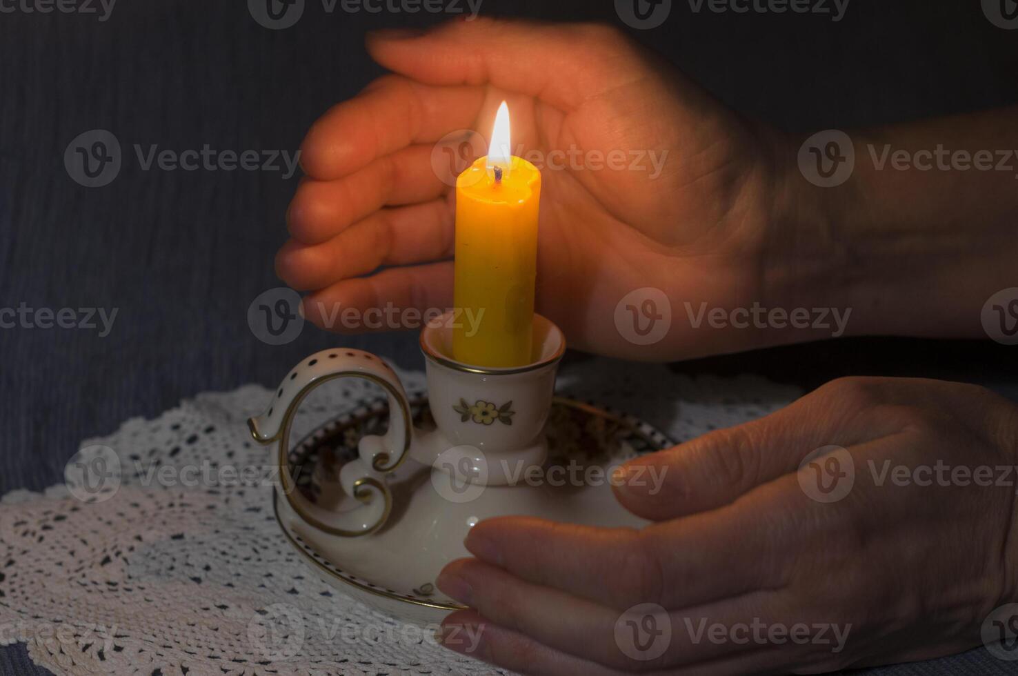 un iluminado vela Entre De las mujeres palmas en el oscuro silencio y condolencias, foto