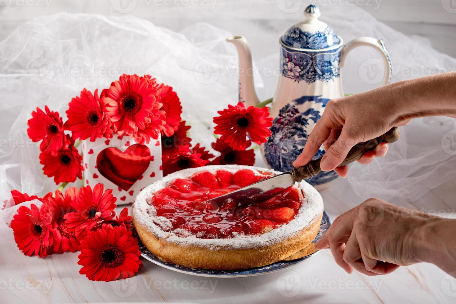 Still life, hand cut strawberry pie on a table decorated with red gerberas for mother's day photo