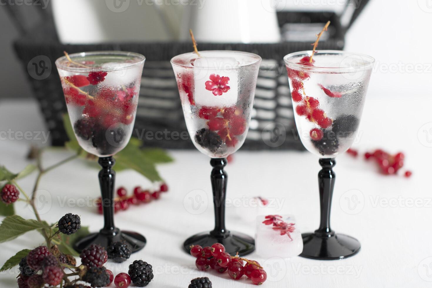 transparent gin and tonic with ice and fresh red currants and blackberries photo