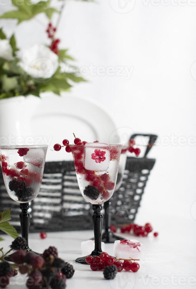 transparent gin and tonic with ice and fresh red currants and blackberries photo