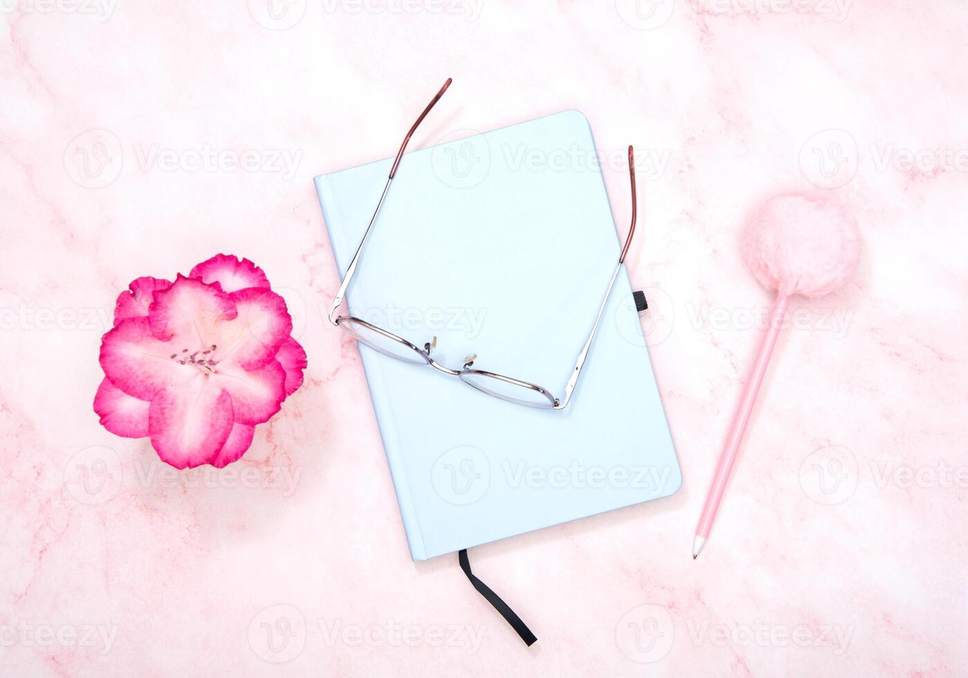 blue notepad with a pen on a pink table, workplace of a female student photo