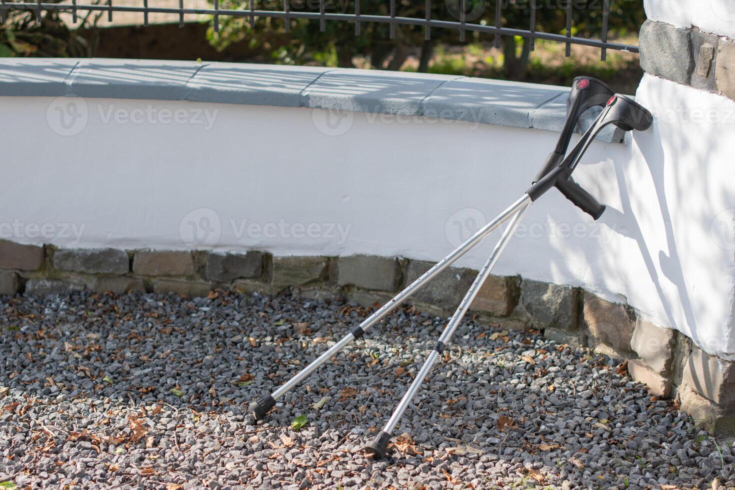 Abandoned crutches leaning against a fence are no longer needed by their owner, concept of recovery photo