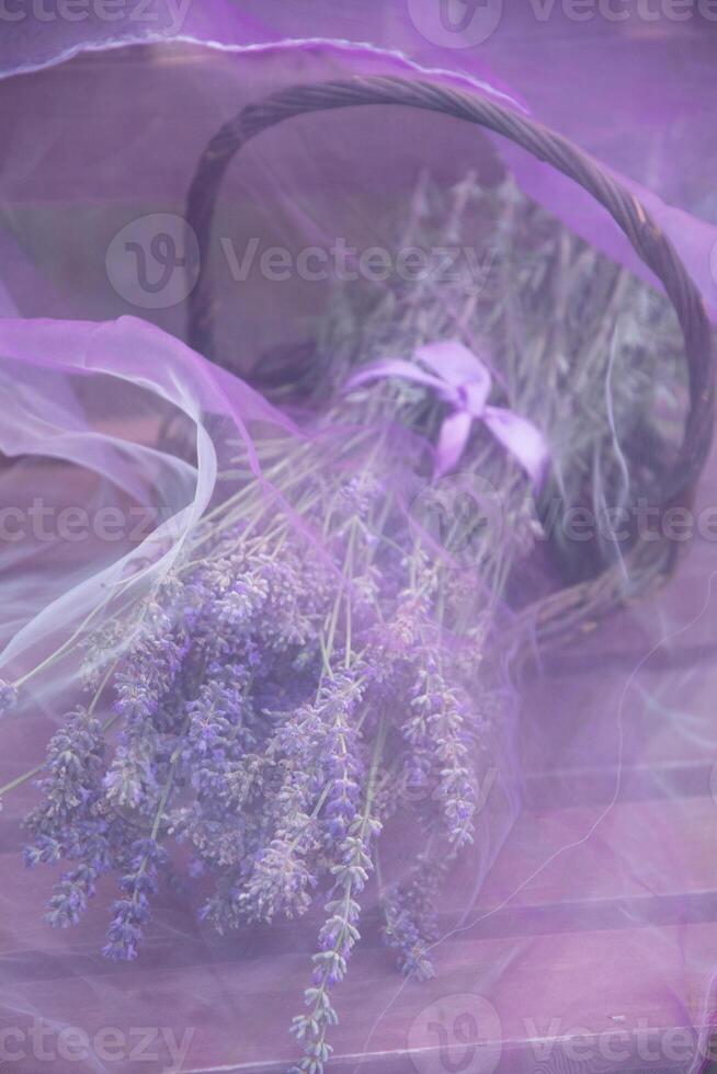 lavender bouquet in a wicker basket under transparent purple chiffon on a wooden photo