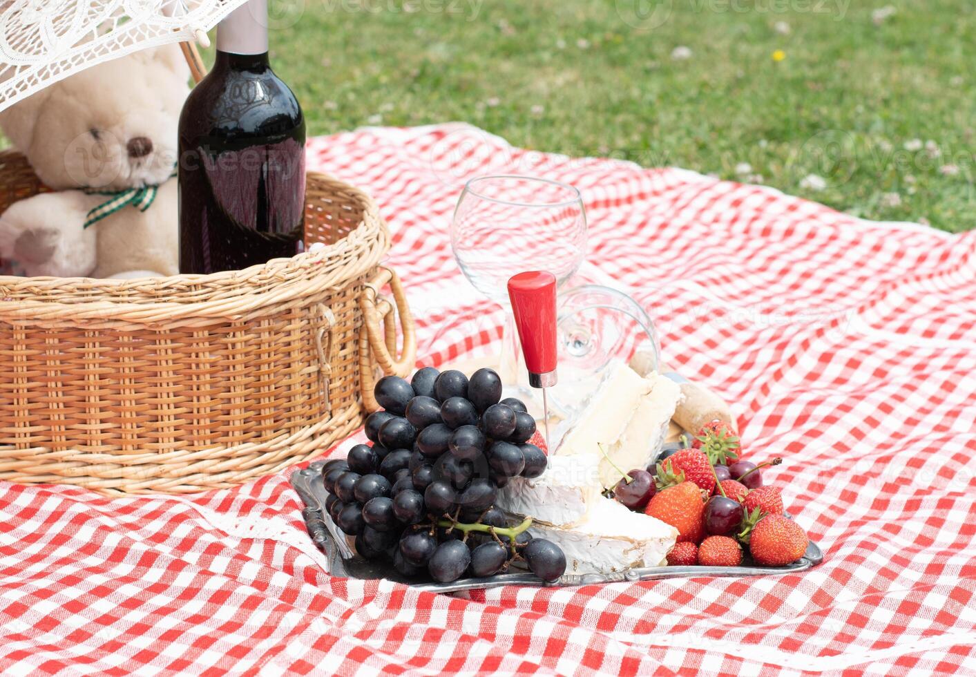 verano picnic en un verde césped con rojo vino, queso y Fresco bayas, uvas foto