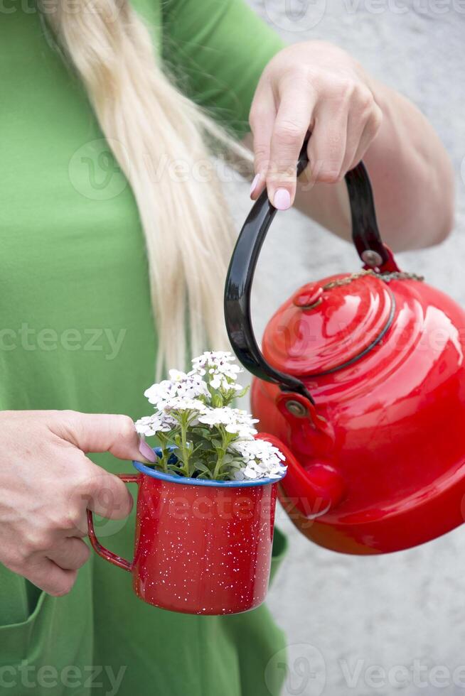 a blonde girl with long hair in a bright green dress holding a red mug photo