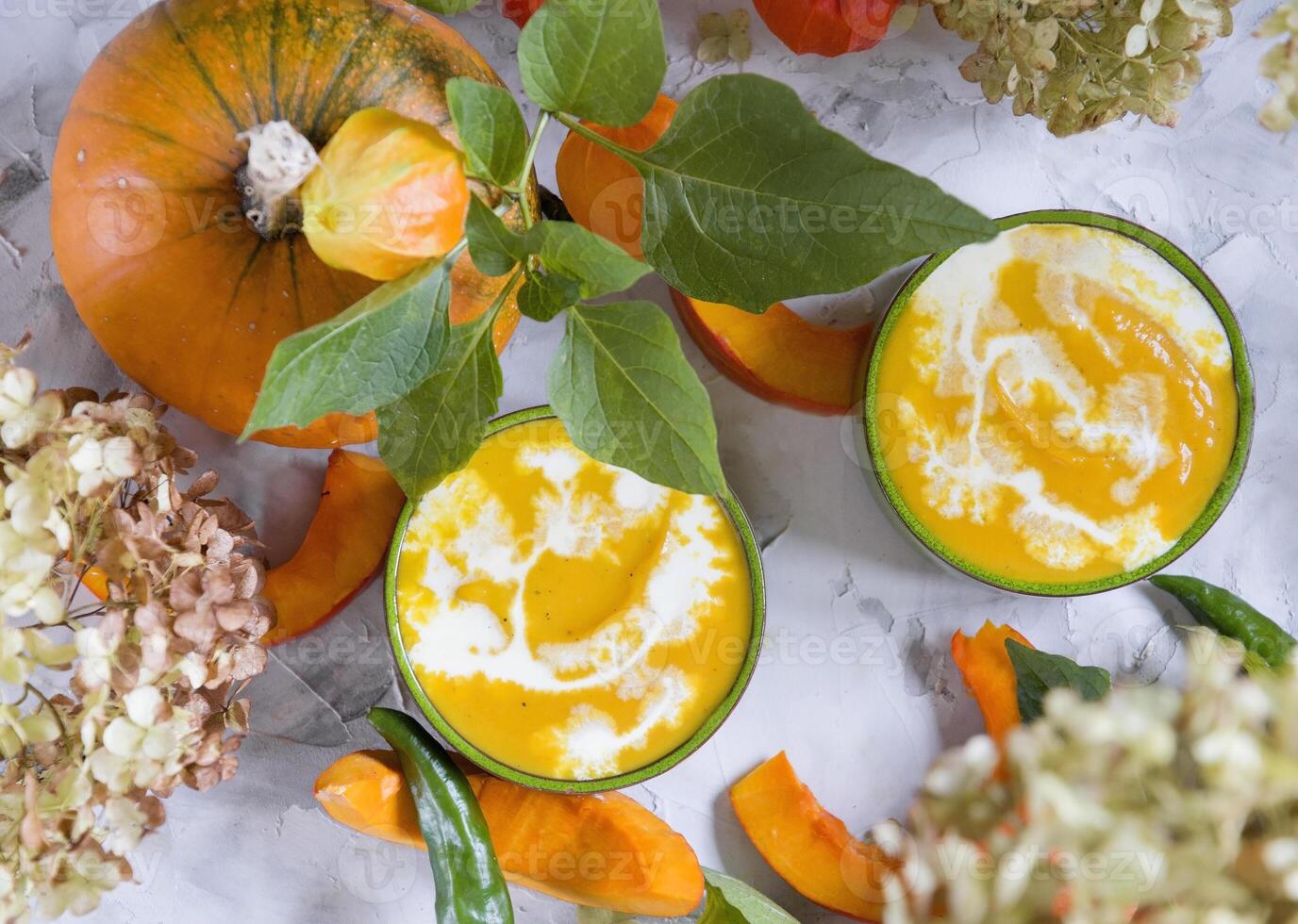 Pumpkin puree soup in green bowls on gray cement background, colorful food, photo