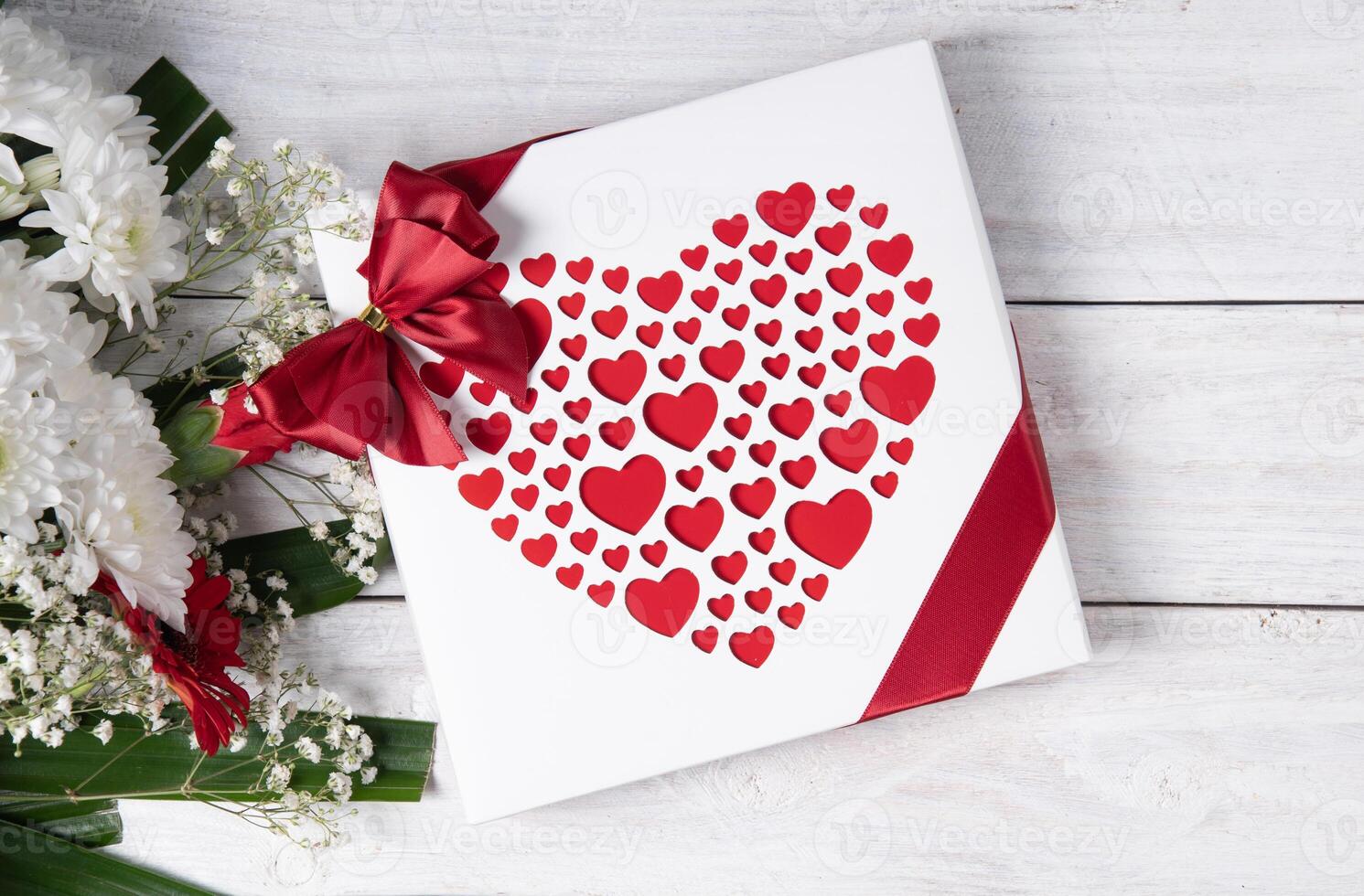 San Valentín día regalo, rojo corazón almendra garapiñada caja y flor ramo de flores en blanco mesa foto