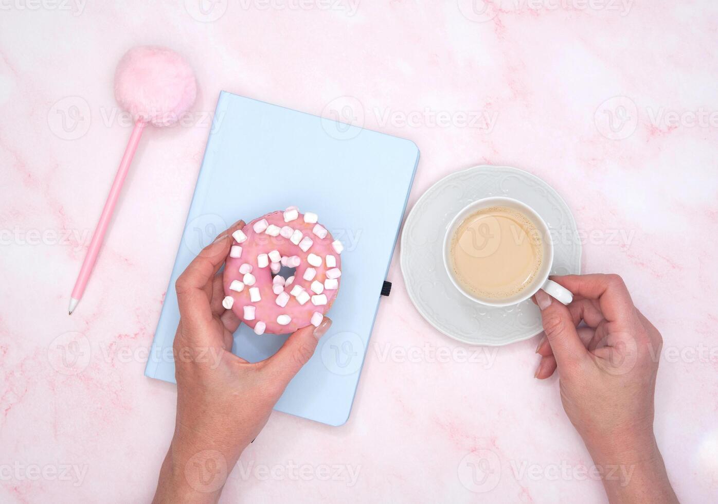 the girl calculates in a notebook the calories of a donut and a cup of coffee photo