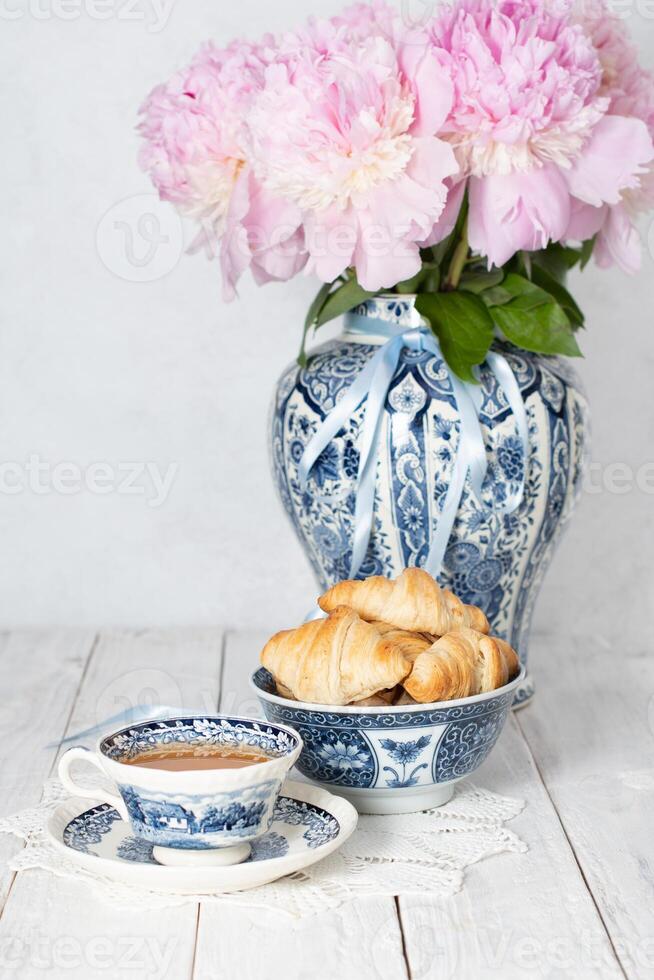 delicate spring still life with croissants and a bouquet of pink peonies photo