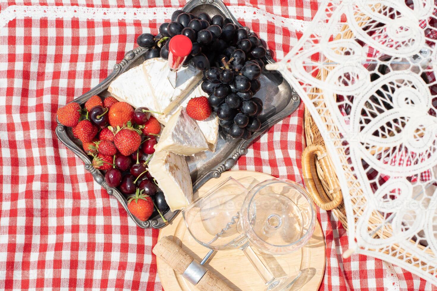 summer picnic on a green lawn with red wine, cheese and fresh berries, grapes photo