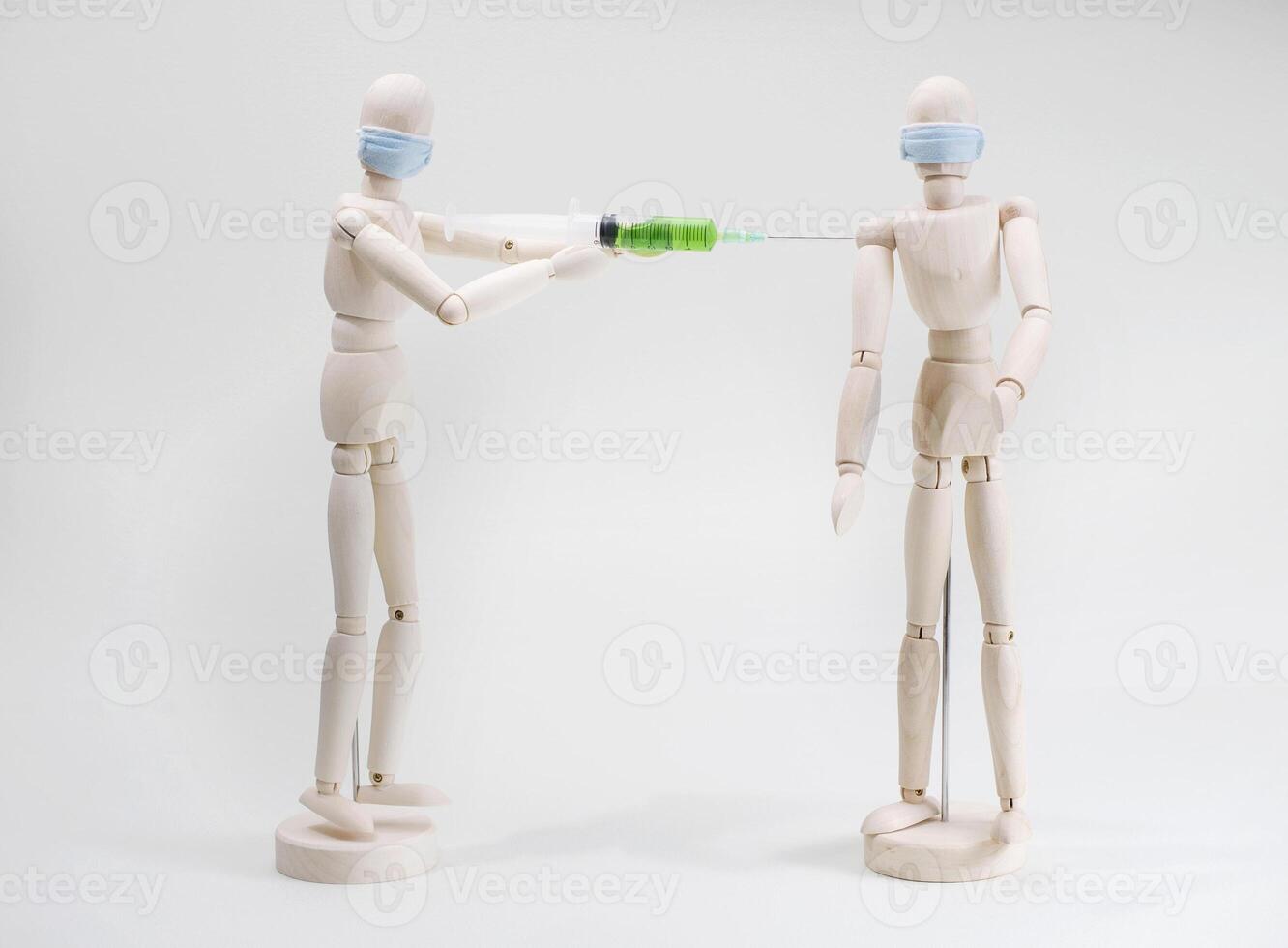 a wooden model of a person vaccinates or injects another person into their shoulder photo