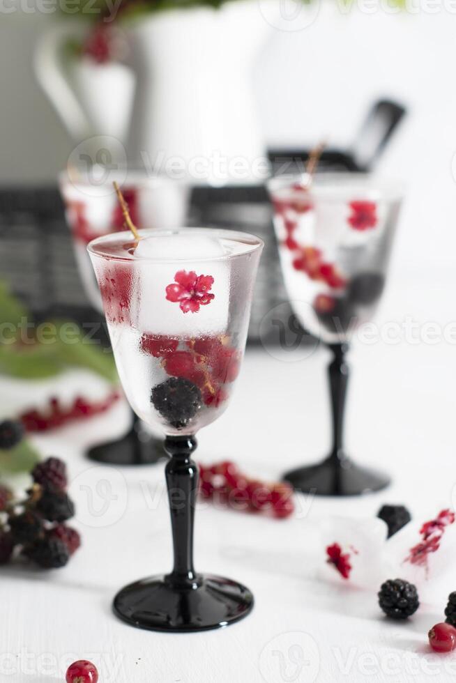 transparent gin and tonic with ice and fresh red currants and blackberries photo