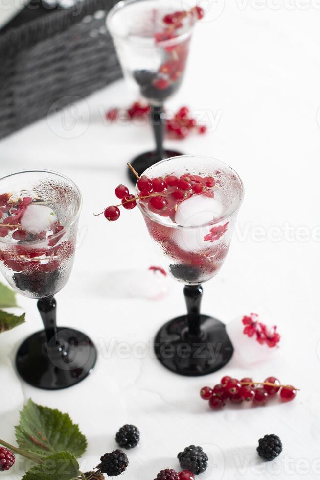 transparent gin and tonic with ice and fresh red currants and blackberries photo