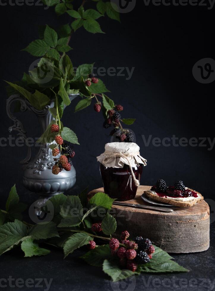 un tarro de Mora mermelada y bruschettas con suave queso y bayas foto