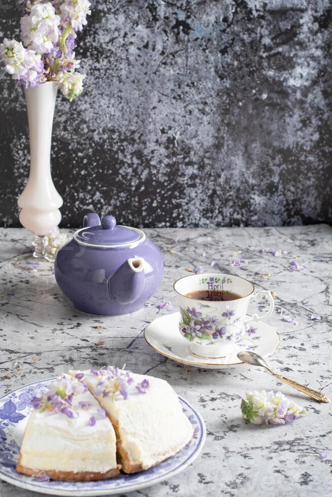 still life with black tea and cheese cake, spring bouquet,delicate lilac flowers photo