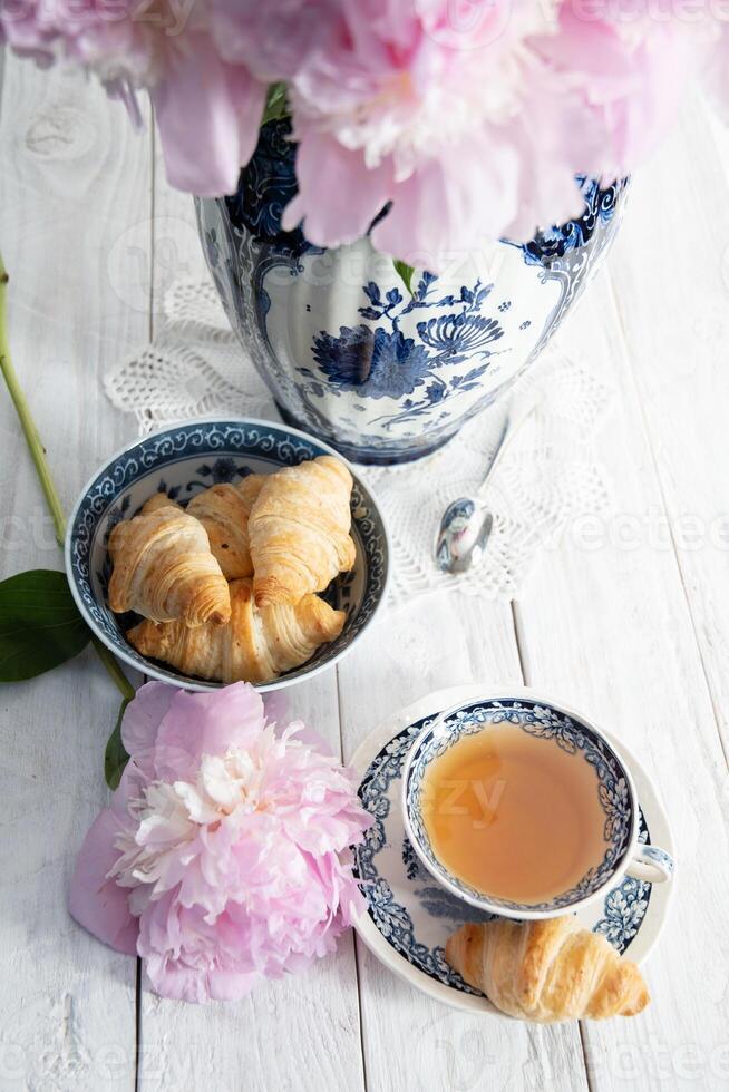 delicado primavera todavía vida con croissants y un ramo de flores de rosado peonías foto