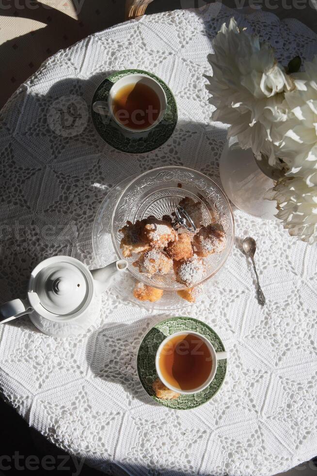 English style tea break, still life with flowers and donuts in the morning sun photo