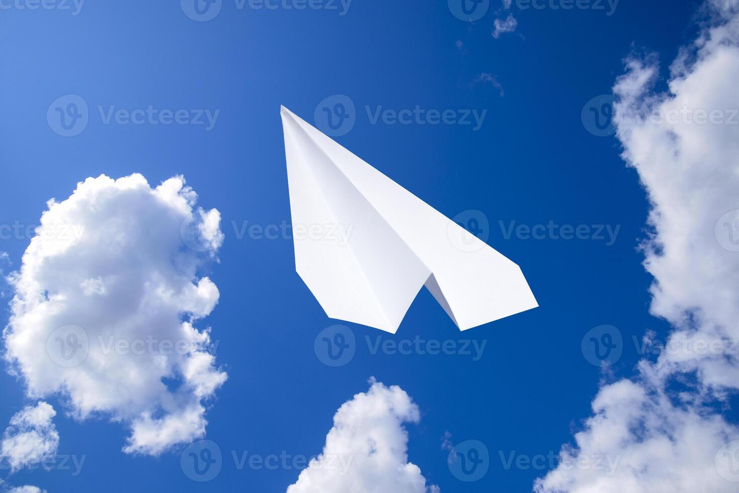 White paper airplane in a blue sky with clouds. The message symbol in the messenger photo