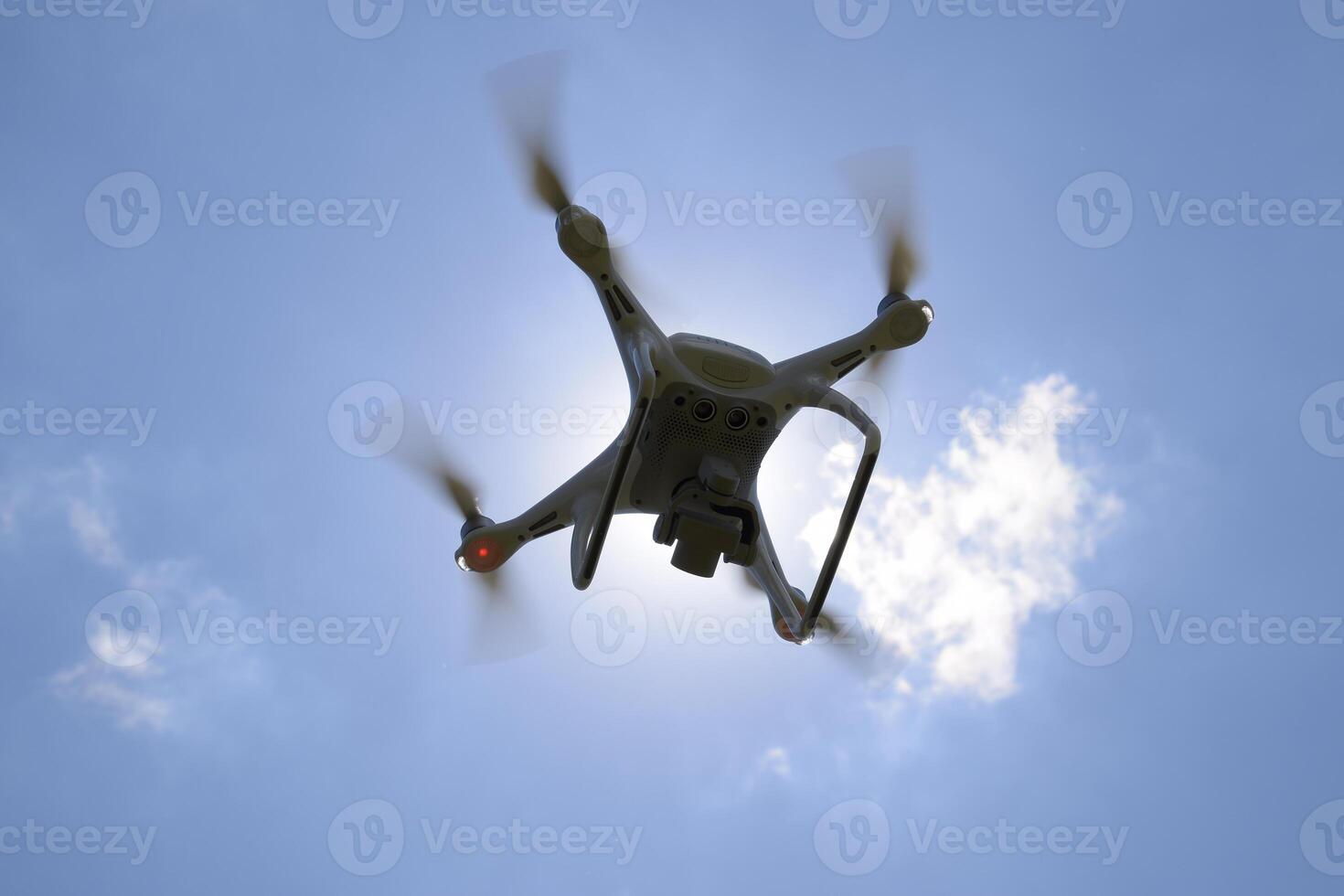Drone DJI Phantom 4 in flight. Quadrocopter against the blue sky with white clouds. The flight of the copter in the sky. photo