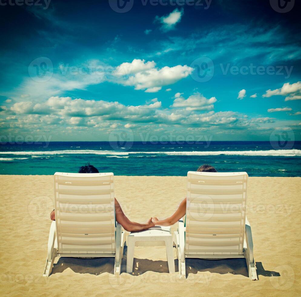 Couple in beach chairs holding hands near ocean photo