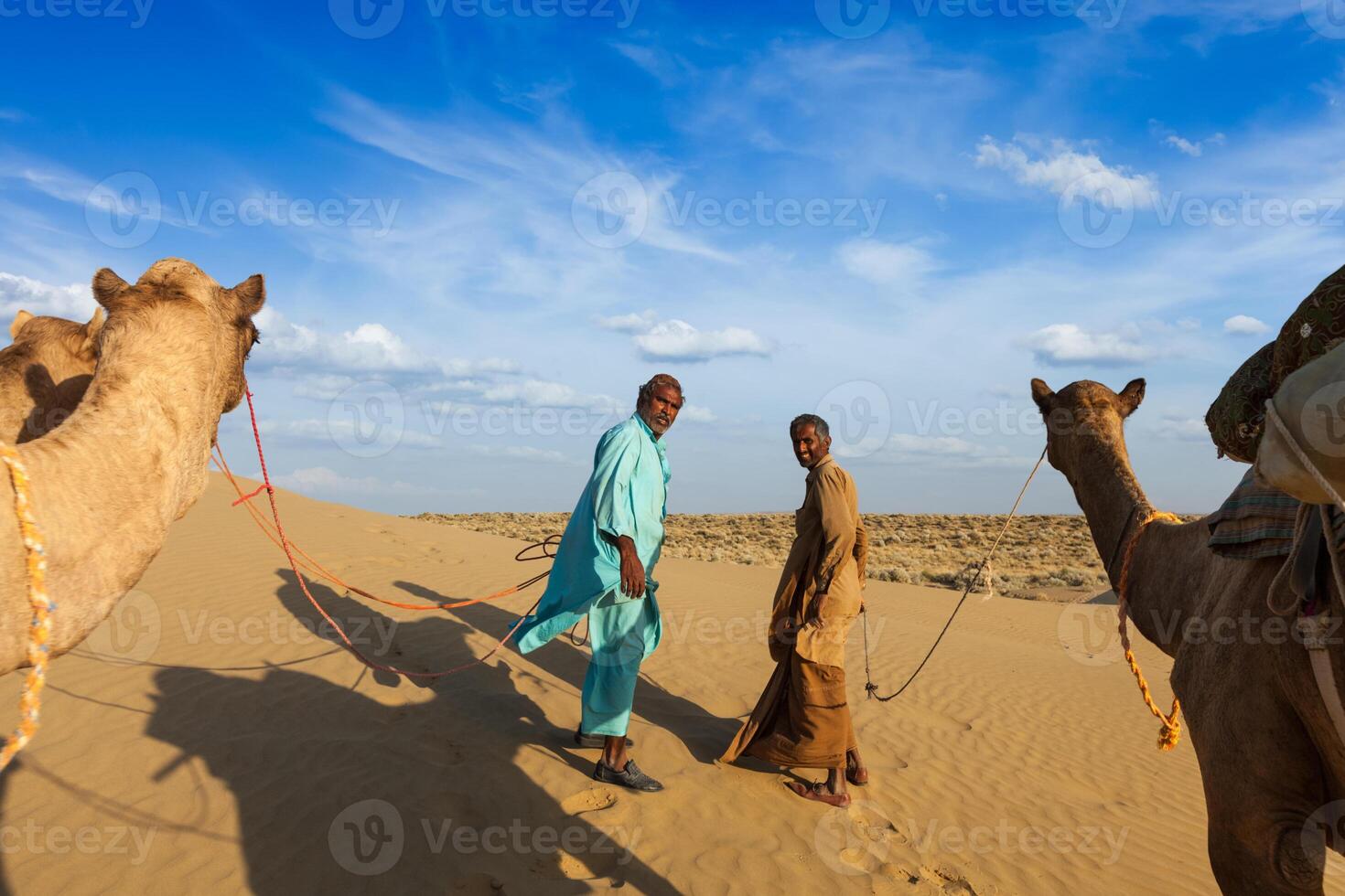 Two cameleers camel drivers with camels in dunes of Thar desert photo