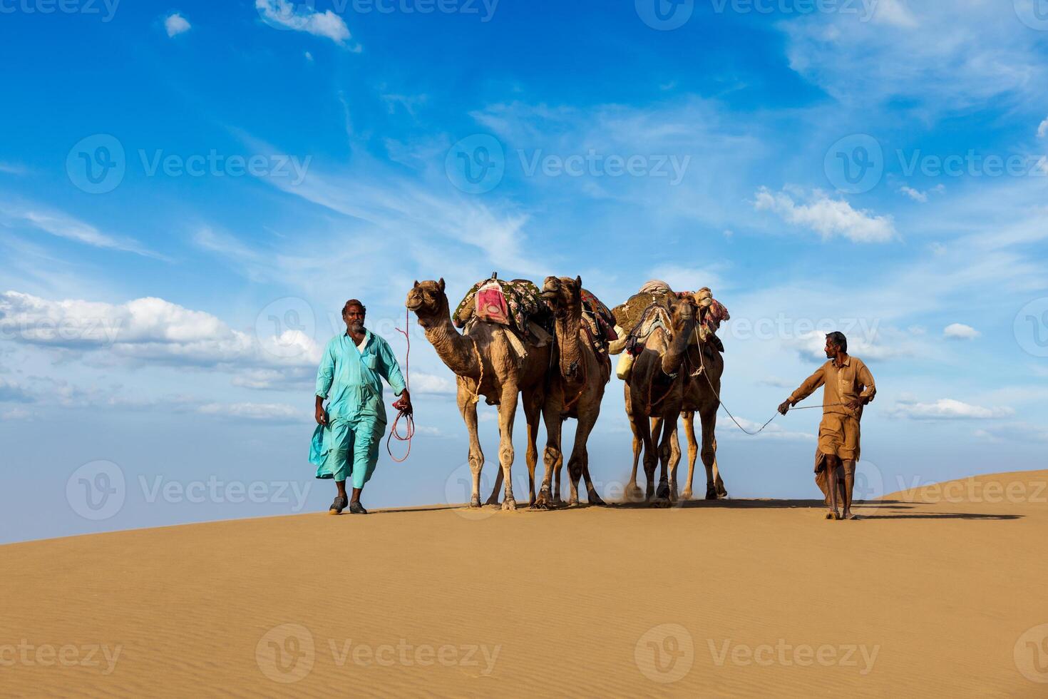 Two cameleers camel drivers with camels in dunes of Thar desert photo